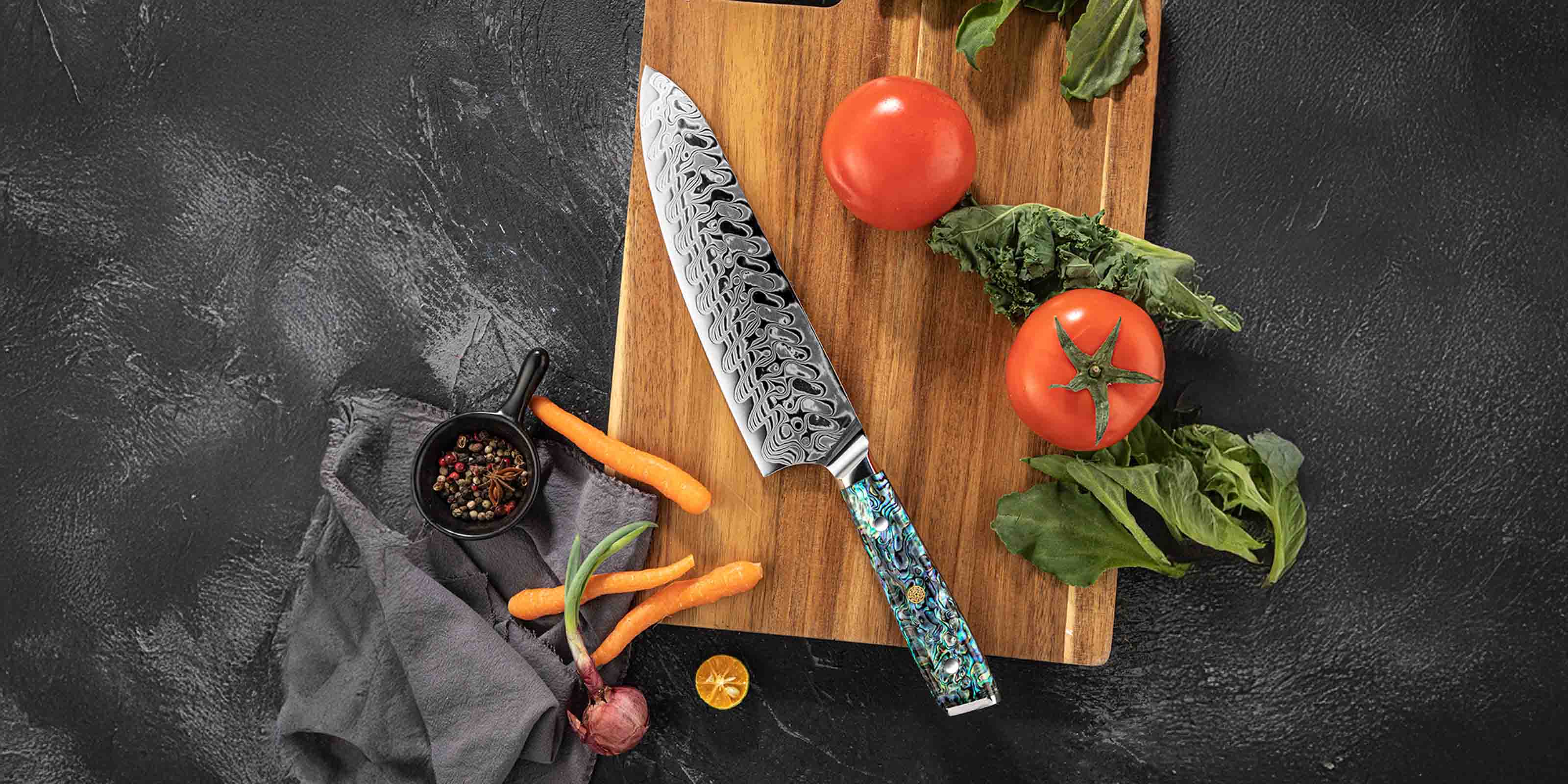 Damascus knife with decorative handle on a wooden cutting board with vegetables on a dark surface